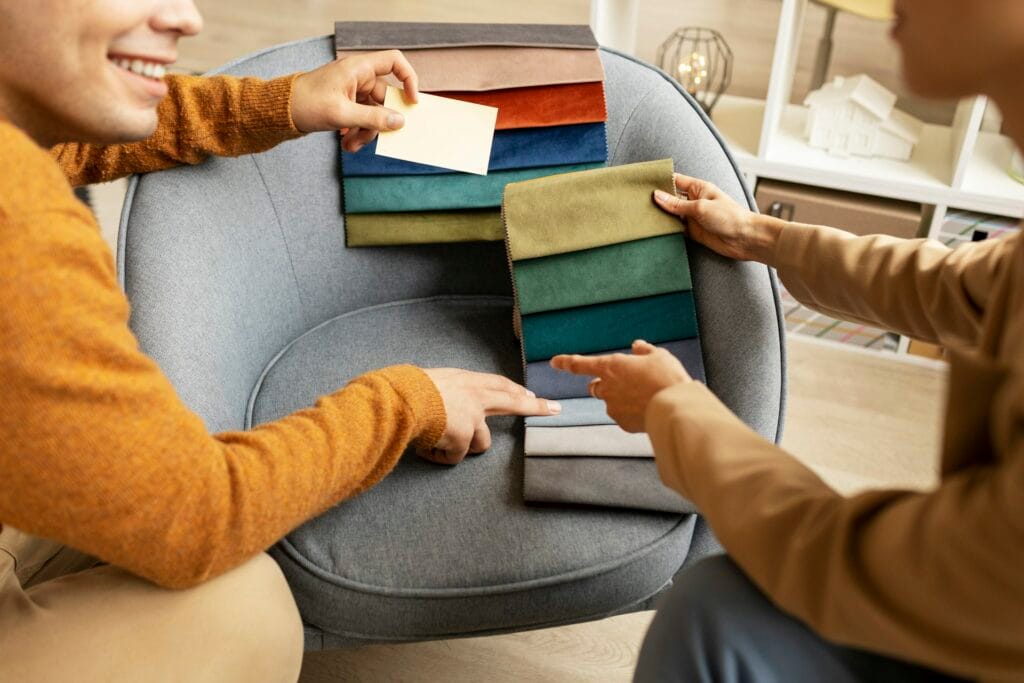 Deux personnes comparant des échantillons de tissu déployés en éventail sur un fauteuil