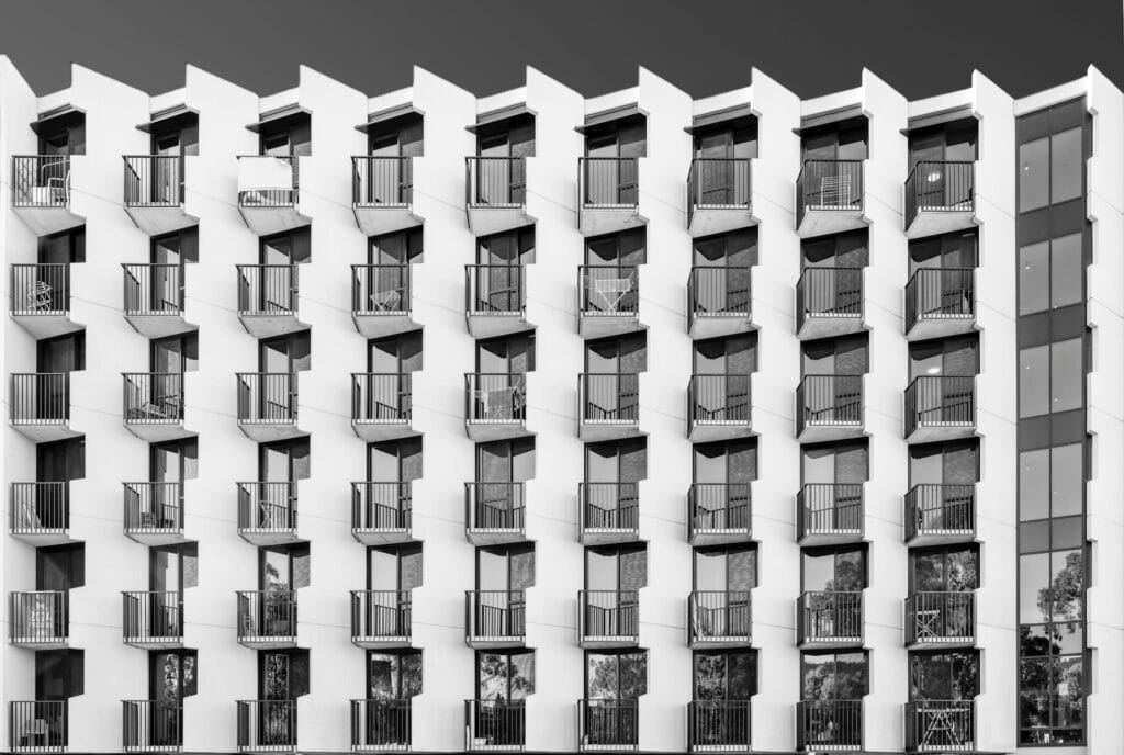 Façade d’immeuble résidentiel en noir et blanc, balcons alignés en damier sur sept niveaux