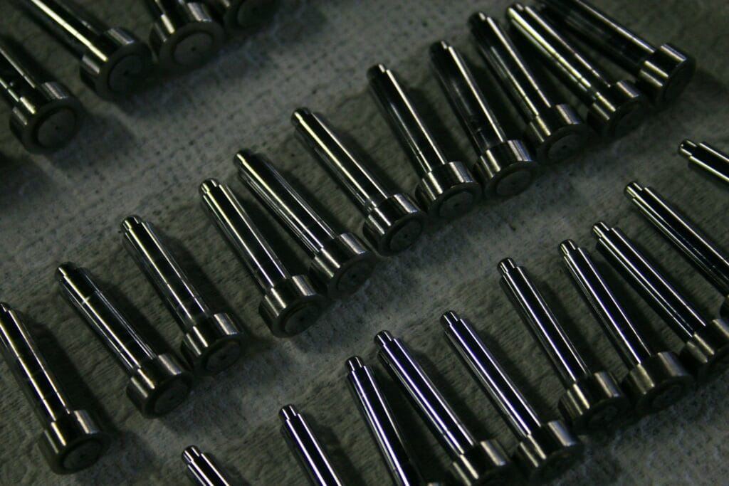 Rangées de pièces métalliques usinées, identiques et alignées sur un plan de travail